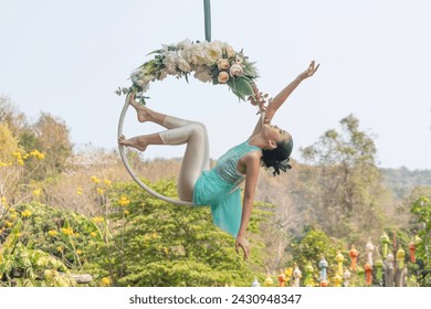 Beautiful Asian woman playing Rig and Hang Aerial Hoop for Yoga in Nature scenery. - Powered by Shutterstock