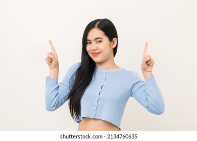 Beautiful Asian Woman Pointing Finger Into Blank Space. Smiling Female Standing Pose On Isolated White Background. Attractive Teenager Girl Around 25 Looking At Empty Space For Advertise Text.