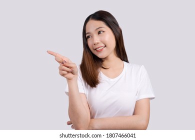 Beautiful asian woman pointing to promotional design copy space, isolated on white background. - Shutterstock ID 1807466041