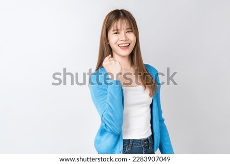 Beautiful Asian woman raises arms and fists clenched with shows strong powerful, celebrating victory expressing success.