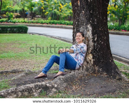 Beautiful Asian woman relaxes in the shade on a bright autumn day