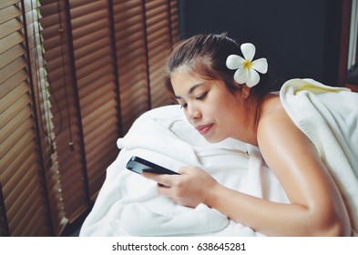 Beautiful Asian Woman Relaxing Using Smart Phone In Spa Massage.