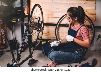 Beautiful asian woman repairman girl ,bike maintenance with happy and replace a bike chain, self bike workshop at home. - Shutterstock ID 2187841929
