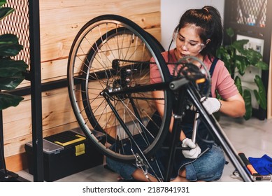 Beautiful asian woman repairman girl ,bike maintenance with happy and replace a bike chain, self bike workshop at home. - Shutterstock ID 2187841931