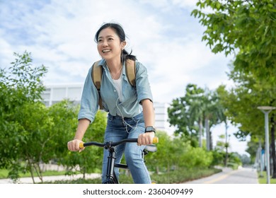 Beautiful Asian woman riding a bicycle through a city park - Powered by Shutterstock