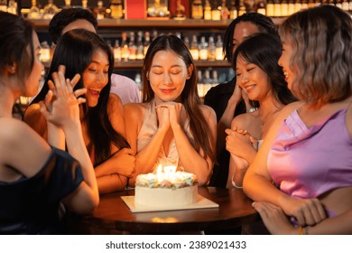 Beautiful Asian Woman is Savoring Her Birthday Festivities at a Restaurant or Bar, Surrounded by Friends Who Have Gathered to Joyfully Celebrate with Her. - Powered by Shutterstock