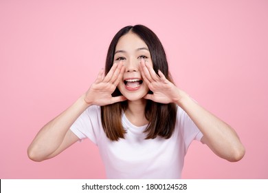 Beautiful Asian Woman Shouting And Looking Up, Using Her Mouth To Tell Something Or Call Someone On A Pink Background.