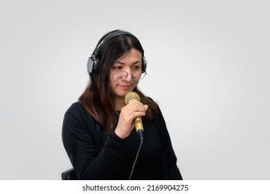 Beautiful Asian Woman Singer. She Enjoying Sing A Song Or Karaoke In Music Studio With Microphone Condenser And Headphones For Fun Or Voice Creative