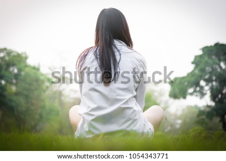 Beautiful asian woman sitting alone in the garden with happiness and relaxing in the evening with sunset time.