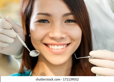 Schöne asiatische Frau, die beim Zahnarzt saß und der Kamera entgegen lächelte