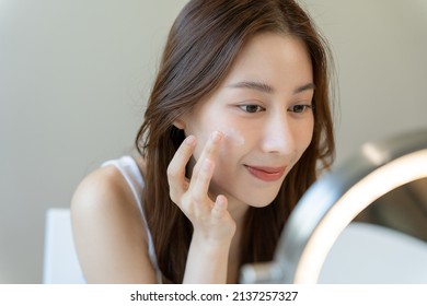 Beautiful Asian woman sitting in front of a mirror. face of a healthy woman applying cream and makeup. Advertisement for skin cream, anti-wrinkle cream, baby face - Shutterstock ID 2137257327
