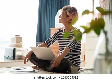 Beautiful Asian Woman Sitting On Bed & Working From Home On Laptop