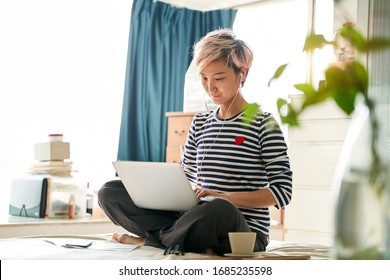 Beautiful Asian Woman Sitting On Bed & Working From Home On Laptop