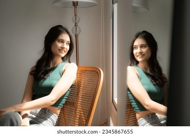 Beautiful asian woman sitting on chair and looking out the window - Powered by Shutterstock