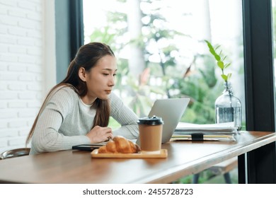 Beautiful Asian woman small business owner A barista is sitting at a table in a coffee shop. After stressing over checking the store's accounts Drink coffee in afternoon to keep from feeling sleepy. - Powered by Shutterstock