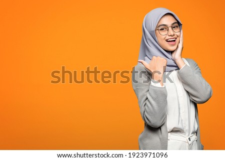 Beautiful Asian woman smiling and pointing to empty space