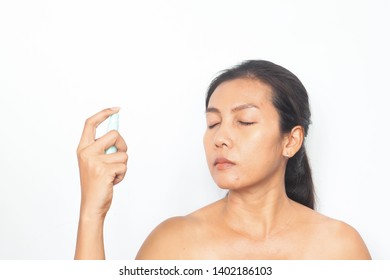 Beautiful Asian woman spraying mineral water on her face. Beauty and health concept