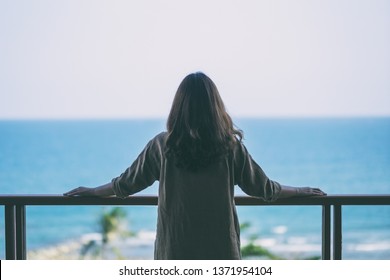 A beautiful asian woman standing and enjoy watching the sea view at balcony