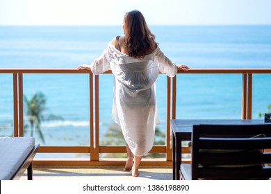 A beautiful asian woman standing and enjoy watching the sea view at balcony 