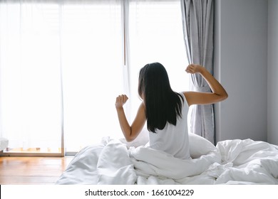 beautiful asian woman stretching on bed after wake up in modern bedroom - Shutterstock ID 1661004229