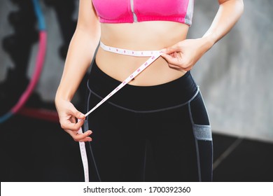 A beautiful Asian woman, Thai people are using a tape measure around the waistline in the gym.