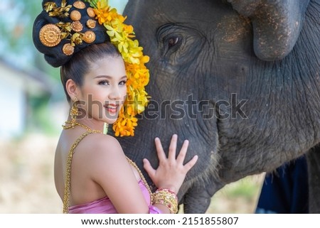 Beautiful Asian Woman with traditional thai dress and her cute elephant, relationship between people and animals.

