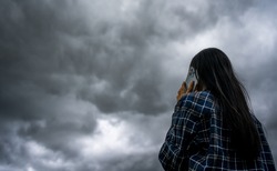Beautiful Asian Woman With Umbrella Talking On The Phone While Raining And Storm Coming.Thunderstorm Depression, Typhoon, Tornado.Dark Cloud Storm. Weather Forecast Outdoor .