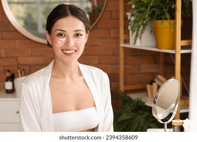 Beautiful Asian woman with under-eye patches in bathroom - Powered by Shutterstock