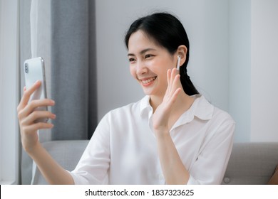 Beautiful Asian Woman Uses Mobile Phone For Video Call Via Internet Connection, Working At Home, New Normal Social Distancing, Coronavirus Outbreak Situation Concept.