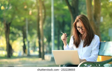 Beautiful Asian Woman Using Laptop Computer In The Park