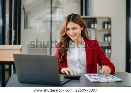 Beautiful Asian woman using laptop and tablet while sitting at her working place. Concentrated at officework.