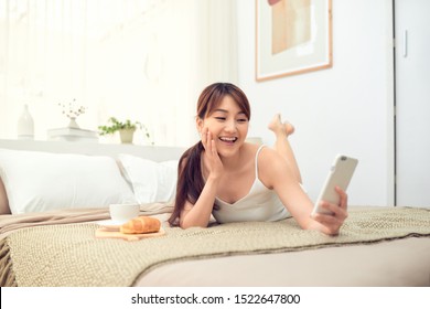 Beautiful Asian Woman Using Mobile Phone To Selfie While Lying On Bed