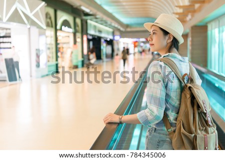 beautiful Asian woman walking around airport. looking window shopping of the duty free shop on the escalator conveyor belt.