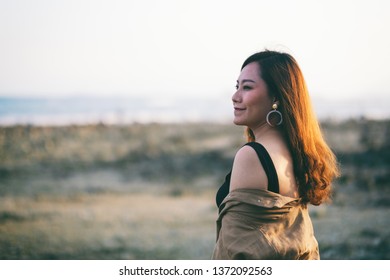 A beautiful asian woman walking on the beach by the seashore