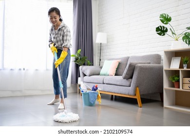 Beautiful Asian woman washing floor with mop in living room. Cleaning service. - Powered by Shutterstock