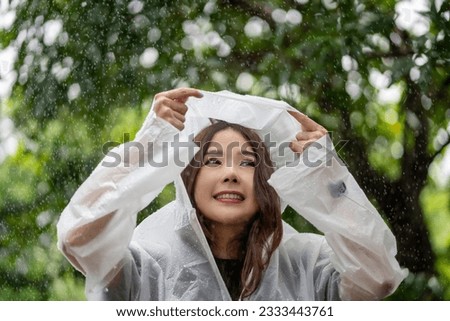 Beautiful asian woman wearing raincoat and enjoying in the rain, Rainy season.