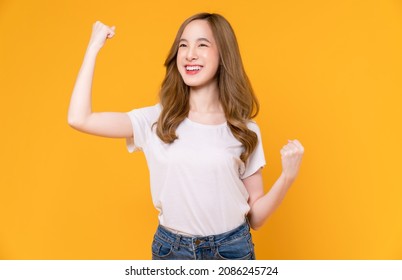 Beautiful Asian Woman In A White T-shirt Raises Arms And Fists Clenched With Shows Strong Powerful, Celebrating Victory Expressing Success.