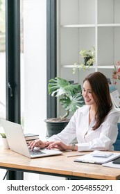 Beautiful Asian Woman Working On Laptop Computer At Office With Happiness. Vertical View.