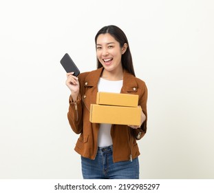 Beautiful Asian Women In Fashion Style Holding A Lot Of Parcel Box And Cell Phone Payment Online Shopping Application On Isolated Background. Attractive Happy Woman In Jacket Going To Shopping