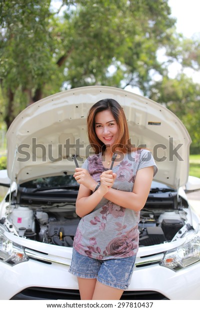 Beautiful  Asian women smiling mechanic using\
tools to work on an\
automobile