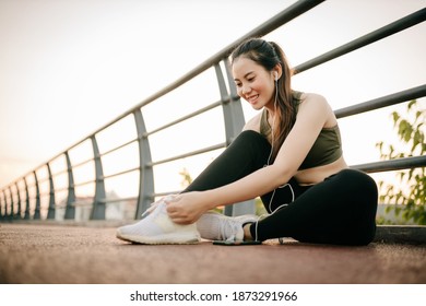 Beautiful Asian Women In Sportswear Listening To Music During Exercise Outdoors In The Park At Sunset. Healthy Women Concept.