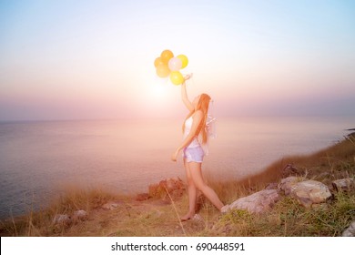 Beautiful Asian women standing on rock beach and holding balloons ,happy time concept - Shutterstock ID 690448591