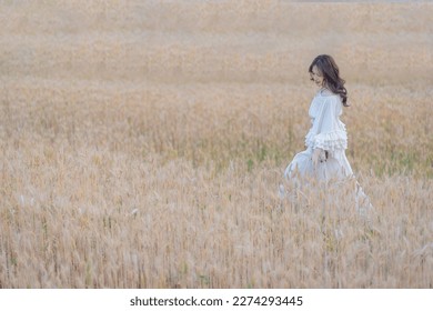 Beautiful Asian women were in white dresses relaxed and happy in the Barley rice field season golden color of the wheat plant. Freedom traveler, dreamy portrait in a wheat field, travel lifestyle.