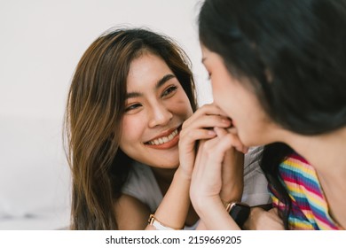 Beautiful Asian Young Lesbian LGBTQ Couple Or Friends Using Computer Laptop Together Smile And Relax On Bed.Happiness LGBTQ Couple Woman Spending Time Together At Home. LGBTQ Pride Month Concept