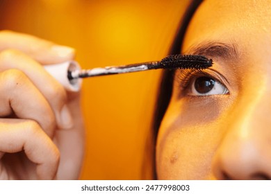 Beautiful Asian young woman applying makeup in front of the mirror. Applying mascara on her eyelashes. Lifestyle people concept. - Powered by Shutterstock