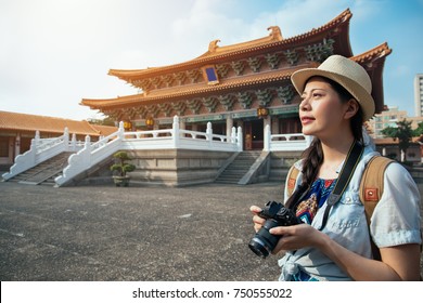 Beautiful asian young woman photographer relaxing on summer holiday near ancient traditional chinese in Taiwan travel destination. Girl in delicate elegant silk sun dress.