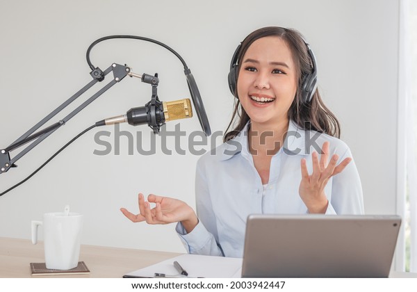 Beautiful asian young woman radio host working,\
setting microphone, preparing to speak before recording podcast and\
live on social media. Technology of on-air online in broadcasting\
at home studio.