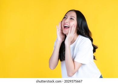 beautiful Asian young woman screams announce the good news or promotion , holding hands near her face with open mouth Herald news promotion isolated on yellow background - Shutterstock ID 2029375667