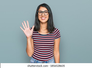 Beautiful Asian Young Woman Wearing Casual Clothes And Glasses Showing And Pointing Up With Fingers Number Five While Smiling Confident And Happy. 