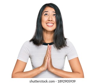 Beautiful asian young woman wearing casual white t shirt begging and praying with hands together with hope expression on face very emotional and worried. begging. 
